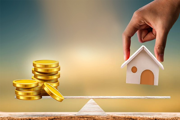 Stacks of coins and a small house model balanced on a seesaw