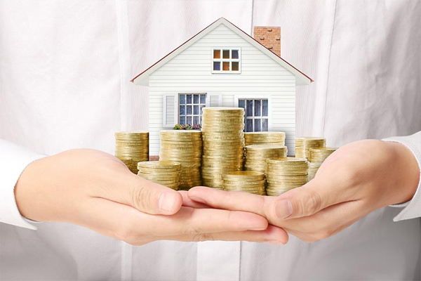 Hands holding stacks of coins with a house model on top